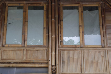 Glass windows with frames and walls made of bamboo in an ecological architectural style house building.