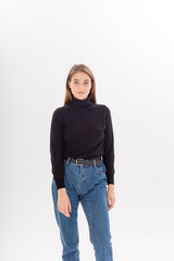 portrait of young attractive caucasian woman with long hair in black turtleneck, blue jeans isolated on white studio background. skinny pretty female posing on cyclorama. model tests of beautiful lady