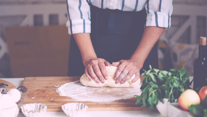 Female hands making dough. Dough with flour, eggs and other utensil, ingredients lies on white wooden table. Baking homemade process.