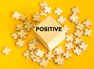 The word POSITIVE written on cube and framed with thought bubble on yellow background. Future aspirations about life, career or business concept.