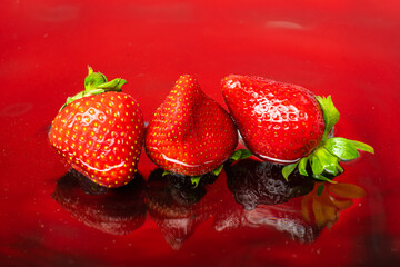 fresh natural strawberries on red background with water