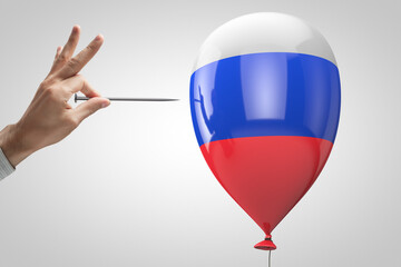Hand with nail trying to puncture the balloon with Russian symbols