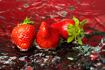 fresh natural strawberries on red background with water