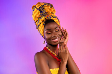 Photo of young happy dark skin lady wear tribal headwrap touch face hands isolated on vivid light background - obrazy, fototapety, plakaty