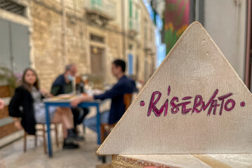 Table with the reserved writing in Italian of an Puglia restaurant. In the blurred background some...