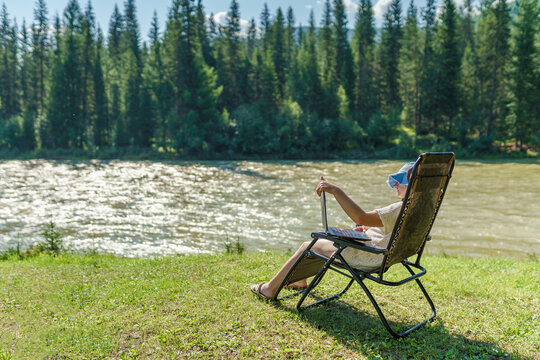 One Person With Laptop On The Beach Of River In Summertime