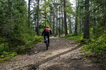 Obraz premium Man Cyclist on sport mountain bike on forest track. Male mountain bike racer cycling on trail with tree roots. Mountain biker rides in spring fresh air forest. Sports motivation and inspiration.