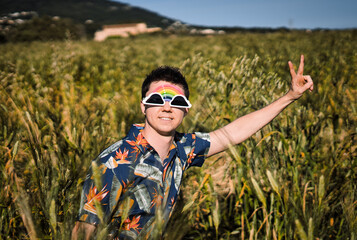 Young man wearing funny sunglasses making the peace sign with his hand and looking at camera in the countryside.