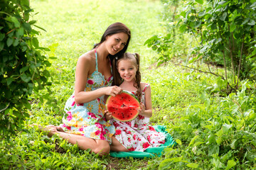 Two smiling girls eats slice of watermelon outdoors on the farm.