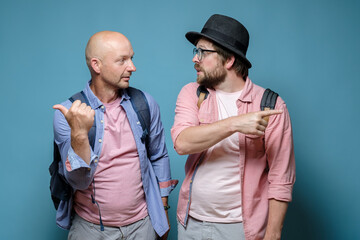 Two tourists with urban backpacks travel and decide where to go next, one points in one direction, the other in the other. 