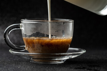 Hot coffee with milk is on a black background.