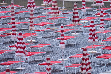 Empty beach loungers with folded umbrellas in Italy