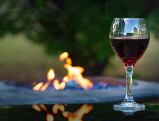 camp fire table with one glass red wine on right. Relaxation at a vineyard or linery. Low key, room for copy