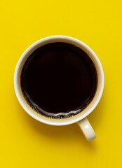 Top view of black coffee cup on yellow background