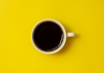 Top view of black coffee cup on yellow background
