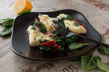round ceramic baking sheet with cod fillet with spinach and sun-dried tomatoes, space for text