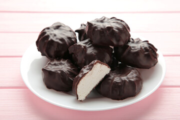 Chocolate covered marshmallows on plate on pink background.