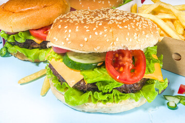 Fastfood, burger party concept. Various delicious burgers set with french fries and sauces on bright blue background flatlay top view copy space