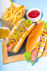 Barbecue grilled fastfood, Various traditional american hot dogs set with sausage, yellow mustard, ketchup and fresh vegetables salad, top view on bright blue background with french fries