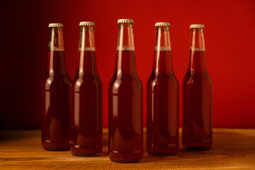 Five bottles of the drink stand on a wooden table against a red background