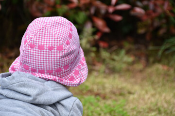 little girl seen from behind with white and pink hat