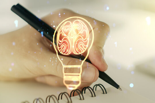 Double exposure of creative light bulb hologram with human brain and with man hand writing in notebook on background, idea and brainstorming concept - Powered by Adobe