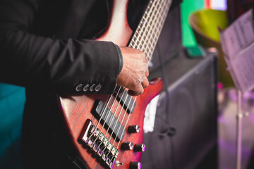 Concert view of an african-american musician with electric bass guitar player during band performing rock music,  bassist player on stage - obrazy, fototapety, plakaty