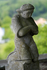 Stone sculpture of praying and kneeling person at fountain at cemetery. Photo taken May 25th, 2021, Zurich, Switzerland.