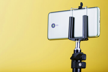 Smartphone on a tripod on a yellow background for blogging.