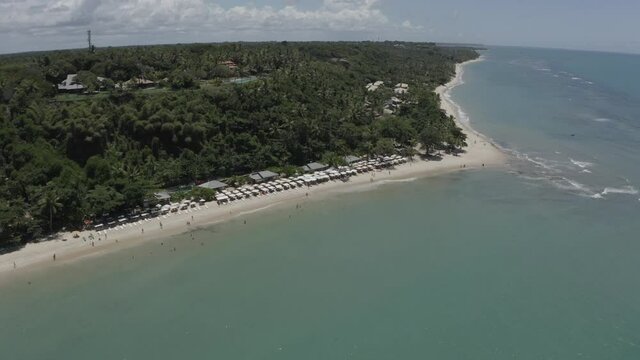 Vue de drone circulaire de l'oc&eacute;an, mar&eacute;e basse, palmiers et parasols. &Eacute;t&eacute; &agrave; Praia Taipe Bahia, Br&eacute;sil. Paysage tropical avec palmiers, sable, eau, coraux, parasols 