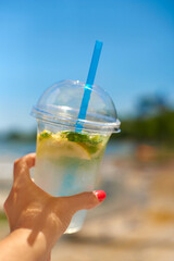 woman hand hold ice fresh summer drink in beach. concept quench thirst. shallow depth of field photo