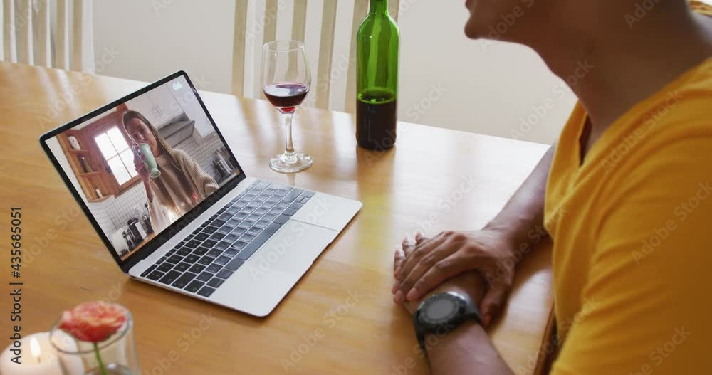 Poster Mid section of african american man with wine having a video call on laptop at home