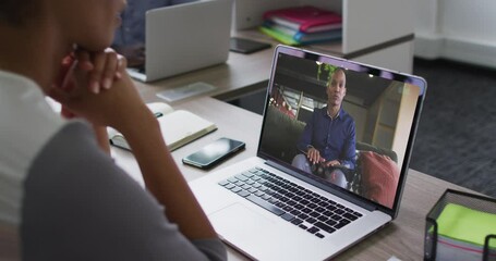 Mid section of african american woman having a video call with male colleague on laptop at office