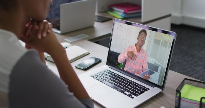 Mid section of african american woman having a video call with male colleague on laptop at office
