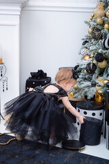 A little girl in dress near cristmas tree