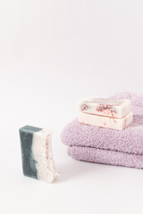 Fototapeta na wymiar Handmade soaps on purple towels on a white background. Minimal cosmetics concept.