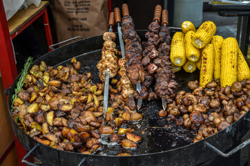 Large frying pan with fried potatoes, mushrooms, corn and barbecue at a street food fair in Kyiv, Ukraine