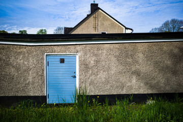 Stockholm, Sweden May 25, 2021 A boue door on a grey concrete wall against a blue sky.