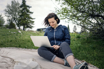 a woman works on a laptop while sitting in nature during the coronavirus pandemic. High quality photo