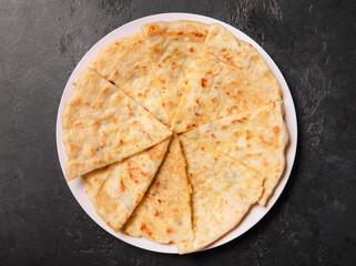 flatbreads with cheese on a dark  background, top view
