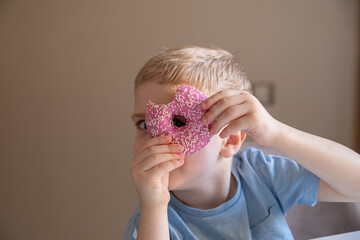The concept is useless food. A little boy eats a pink doughnut at home and looks into the hole of...
