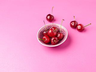 Bowl of fresh cherries on a pink background