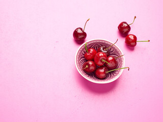 Bowl of fresh cherries on a pink background