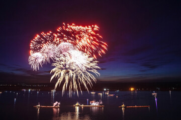 Holiday fireworks above water with reflection on the black sky background