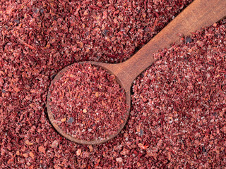 wood spoon on pile of sumac powder closeup