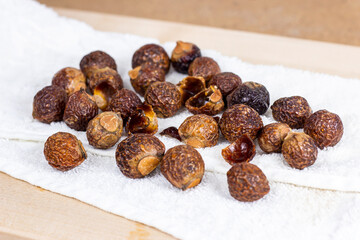 Brown dry soap nuts (Soapberries, Sapindus Mukorossi) for organic laundry and gentle natural skin care on light background.