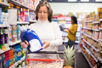 Casual aged woman doing shopping in grocery department of supermarket