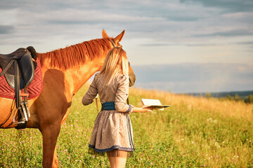girl with book in the field. woman walking with horse