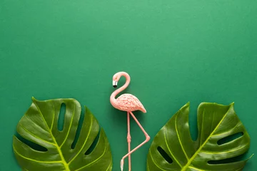 Badkamer foto achterwand  Summer beach party concept. Pink flamingo and tropical leaf monstera on green background. Flat lay, copy space. © Svetlana Kolpakova