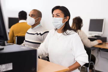 Portrait of latin american woman in protective mask studying in computer class in public library during coronavirus pandemic